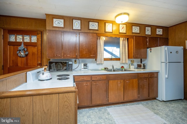 kitchen featuring wood walls, sink, and white appliances