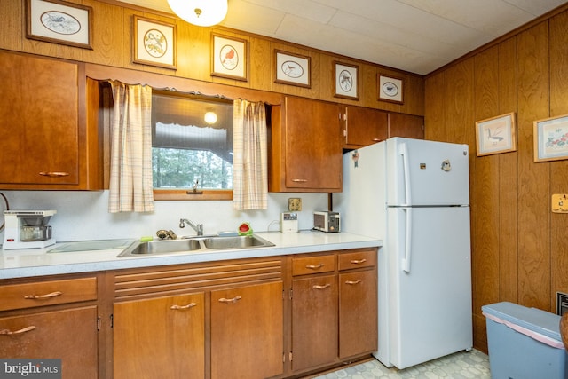 kitchen featuring wood walls, white fridge, and sink