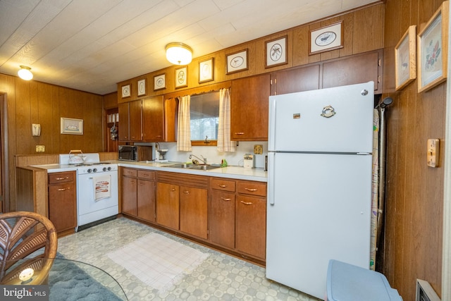 kitchen with sink, white appliances, and wood walls