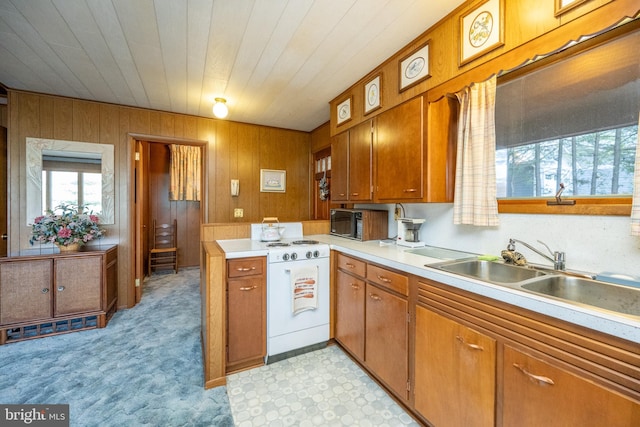 kitchen featuring sink, white stove, wooden ceiling, and wooden walls