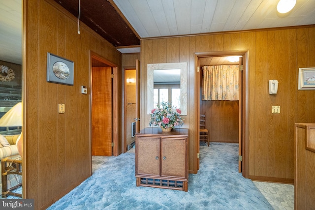 hall featuring wood walls and light colored carpet