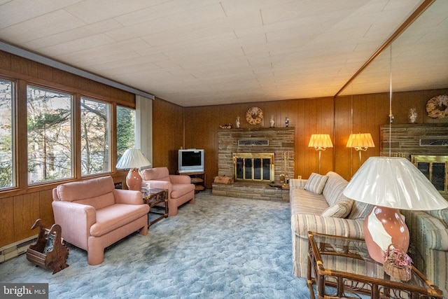 carpeted living room with wood walls, a baseboard heating unit, and a fireplace