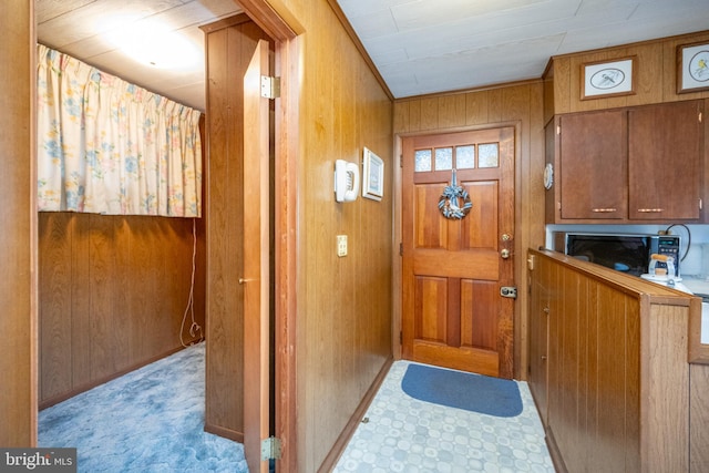 doorway with light carpet and wooden walls