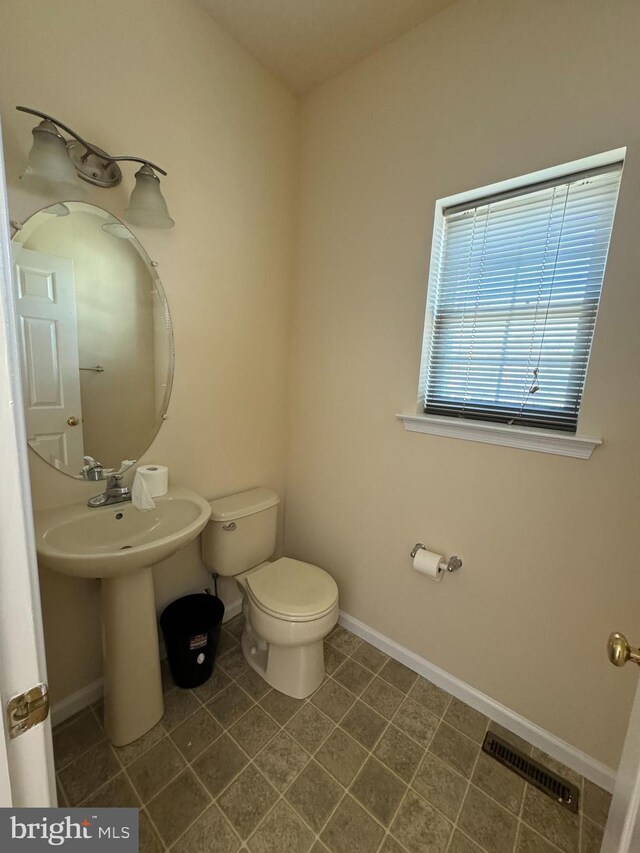 bathroom featuring toilet, sink, and tile patterned flooring