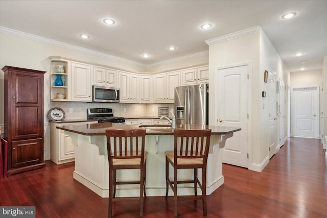 kitchen featuring dark wood-type flooring, appliances with stainless steel finishes, and an island with sink