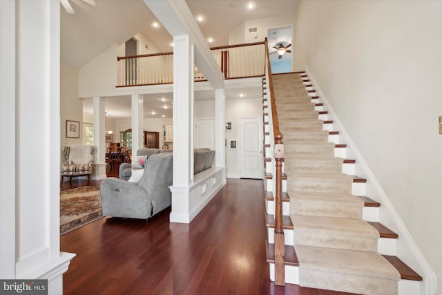 stairway featuring hardwood / wood-style floors, high vaulted ceiling, and decorative columns