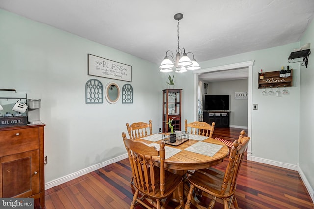 dining area with dark wood-type flooring and a notable chandelier