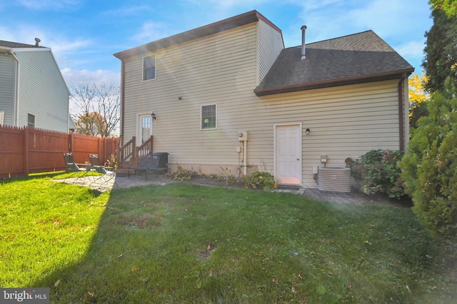 rear view of property featuring a lawn and cooling unit