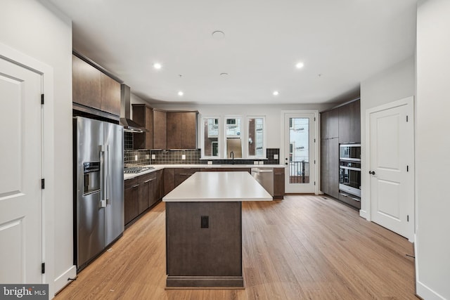 kitchen with backsplash, a kitchen island, light wood-type flooring, dark brown cabinetry, and stainless steel appliances