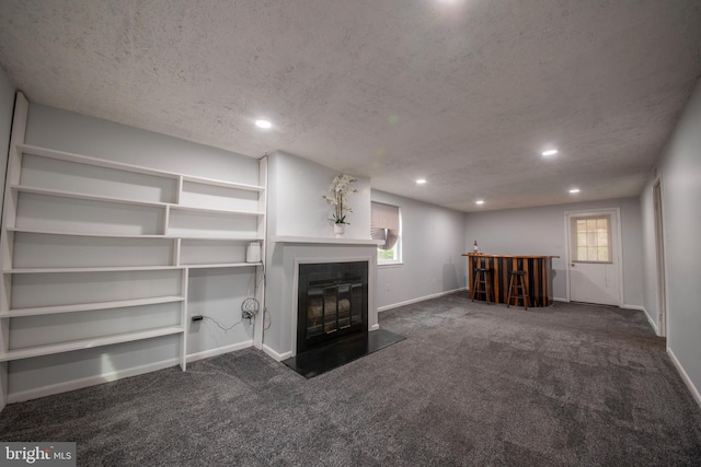 unfurnished living room featuring a textured ceiling and dark colored carpet