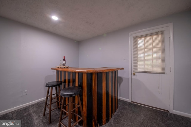 bar featuring a textured ceiling and dark colored carpet