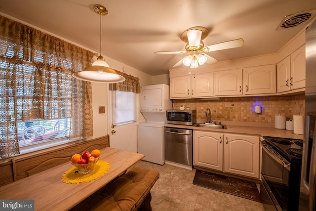 kitchen featuring sink, white cabinetry, stainless steel appliances, stacked washer and dryer, and pendant lighting