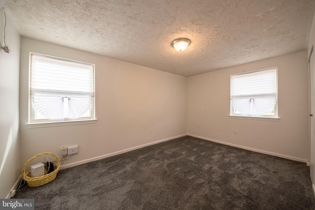 unfurnished room featuring a textured ceiling and dark carpet