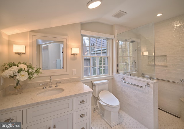 bathroom featuring toilet, vanity, a tile shower, and tile patterned floors