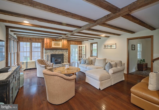 living room with a wealth of natural light, beamed ceiling, dark wood-type flooring, and a wood stove