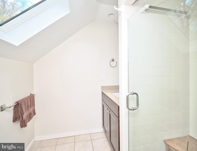 bathroom with a shower with door, vaulted ceiling with skylight, vanity, and tile patterned floors