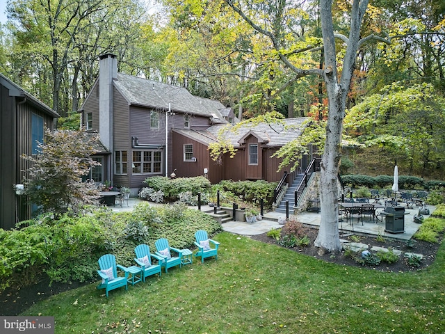 back of property featuring a patio area, an outdoor fire pit, and a lawn