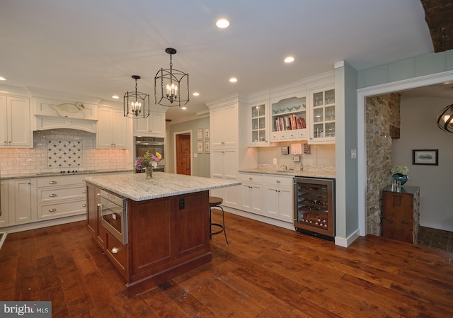 kitchen with wine cooler, a kitchen island, white cabinetry, dark hardwood / wood-style floors, and stainless steel appliances