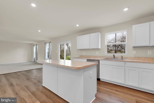 kitchen with light hardwood / wood-style flooring, white cabinets, stainless steel dishwasher, and sink