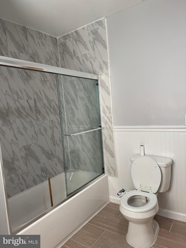 bathroom featuring enclosed tub / shower combo and toilet