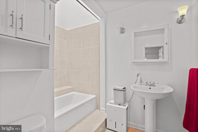 bathroom with tile patterned flooring, tiled shower / bath combo, and toilet