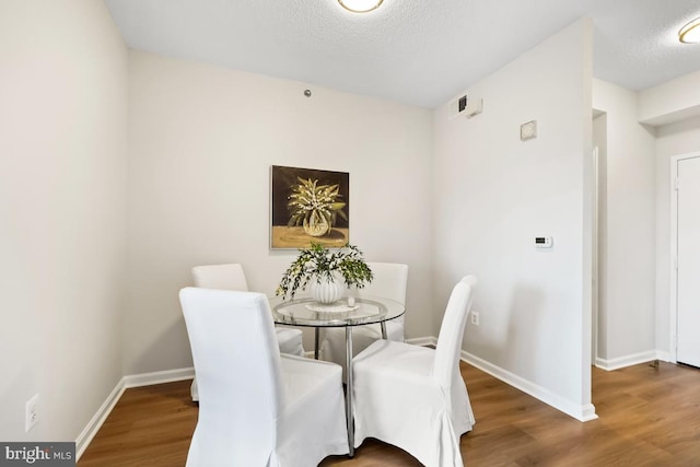 dining area featuring wood-type flooring and a textured ceiling