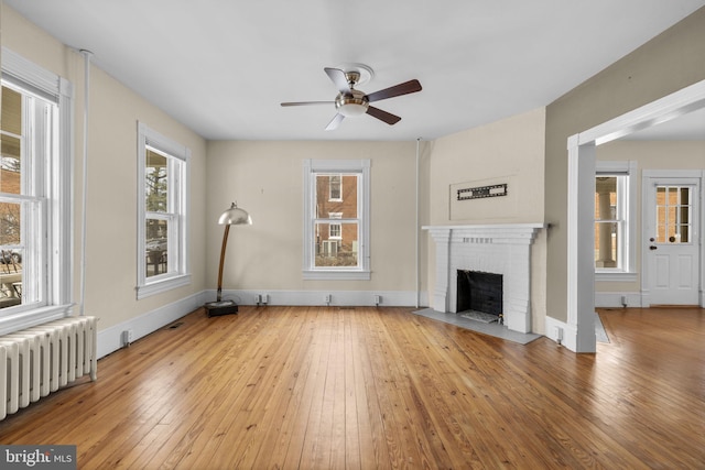 unfurnished living room featuring light wood-type flooring, radiator heating unit, a fireplace, and baseboards