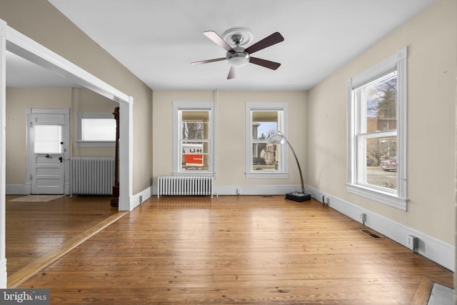 interior space with radiator, ceiling fan, baseboards, and wood finished floors