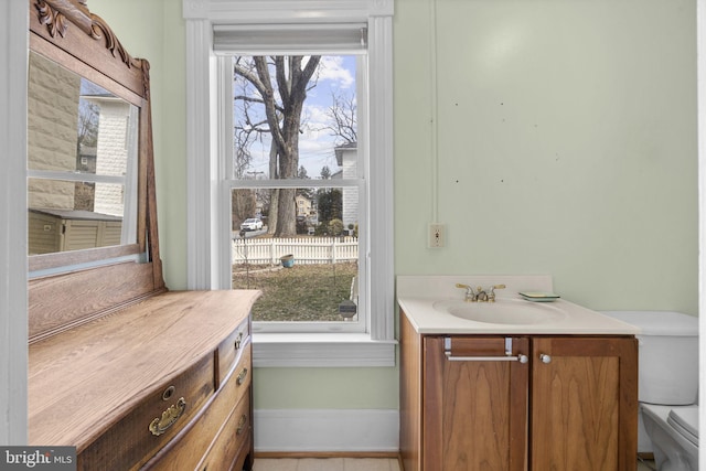 bathroom featuring toilet, baseboards, a wealth of natural light, and vanity