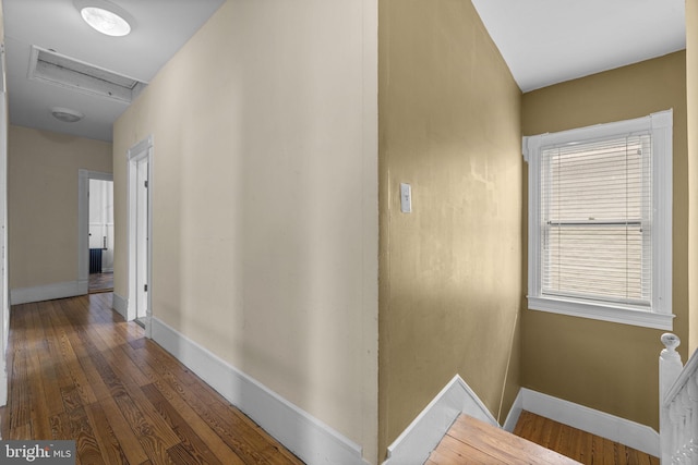 corridor featuring attic access, dark wood finished floors, and baseboards