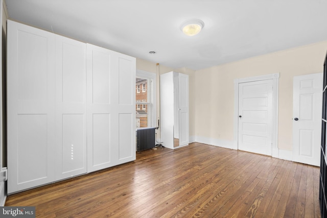 unfurnished bedroom featuring radiator heating unit and dark wood finished floors