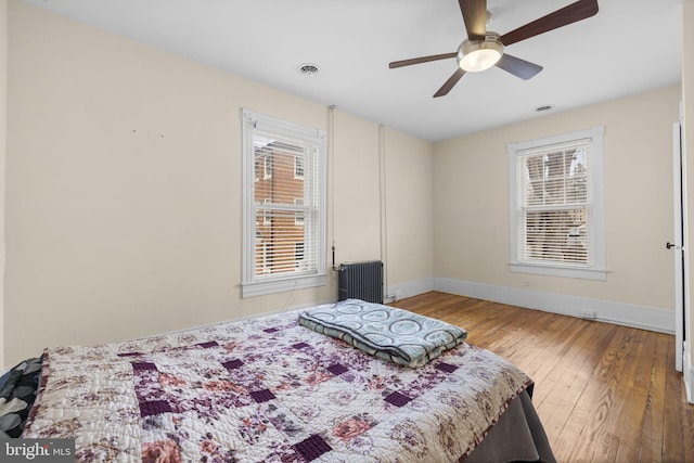 bedroom with multiple windows, baseboards, and wood finished floors