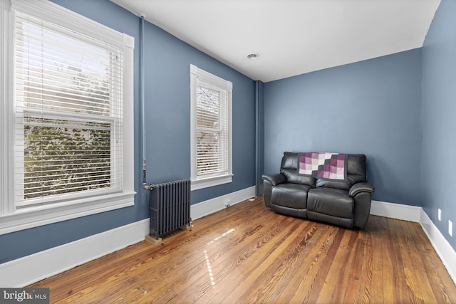 sitting room with radiator heating unit, wood finished floors, and baseboards