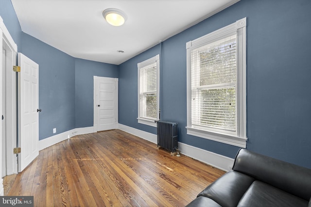 interior space featuring dark wood-style flooring, baseboards, and radiator heating unit