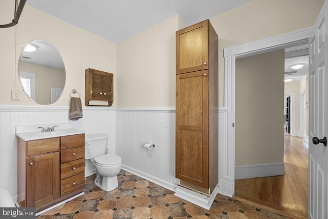 bathroom with a wainscoted wall, vanity, and toilet