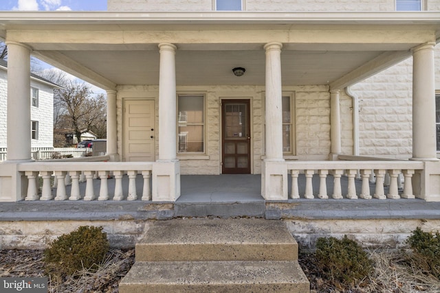 view of exterior entry featuring a porch and stone siding