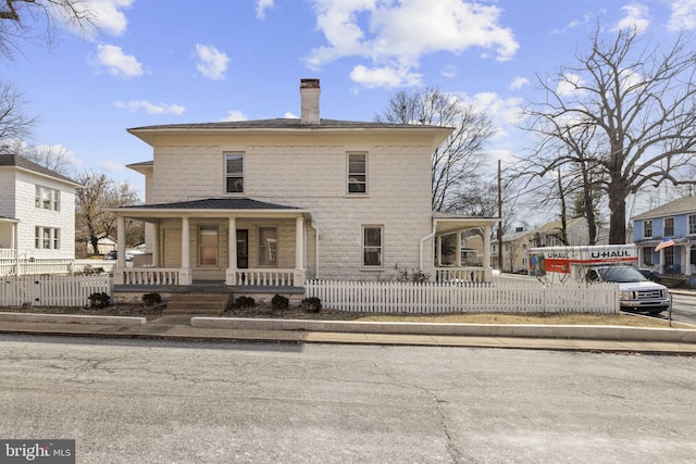 view of front of home with a fenced front yard, covered porch, and a chimney