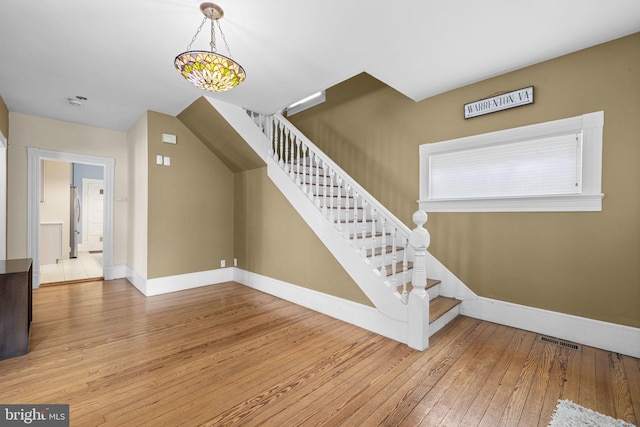 staircase featuring wood finished floors, visible vents, and baseboards