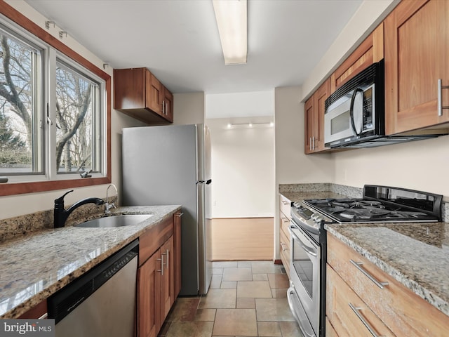 kitchen featuring light stone countertops, appliances with stainless steel finishes, and sink