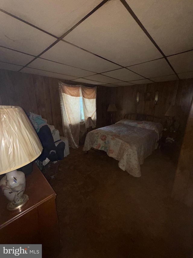 bedroom with a paneled ceiling, carpet flooring, and wooden walls