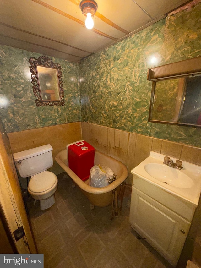 bathroom featuring vanity, toilet, and wood walls