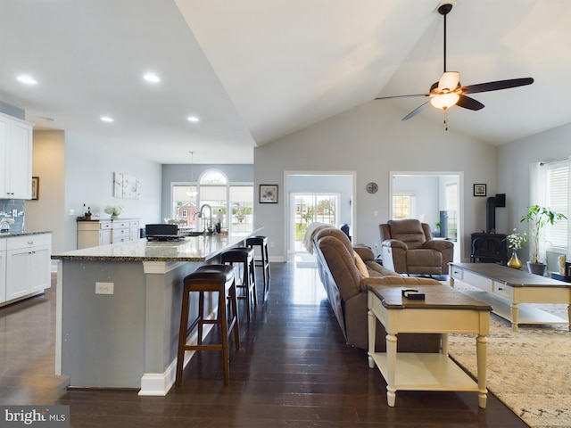 living room featuring sink, ceiling fan, vaulted ceiling, and dark hardwood / wood-style floors