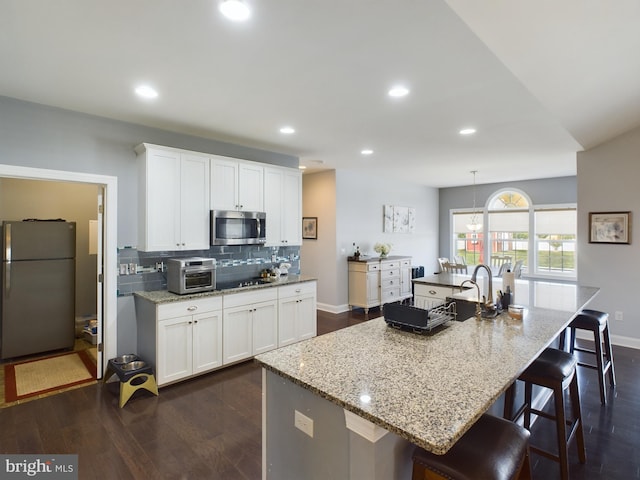 kitchen featuring a center island with sink, white cabinetry, stainless steel appliances, and dark hardwood / wood-style flooring