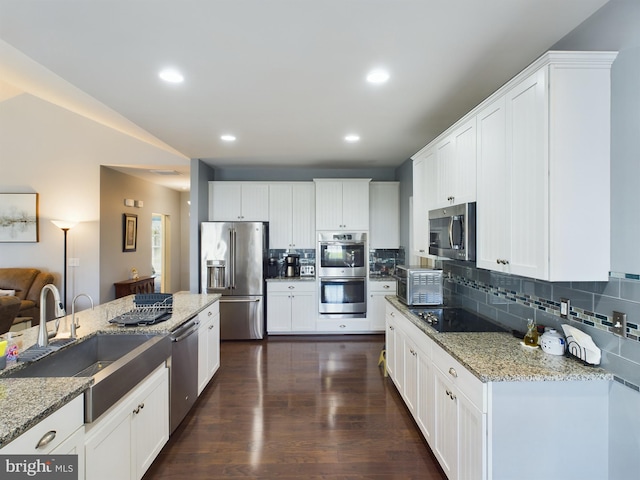 kitchen with light stone countertops, sink, white cabinetry, and stainless steel appliances