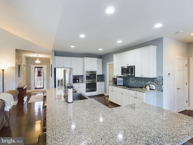 kitchen featuring a large island with sink, sink, dark hardwood / wood-style flooring, stainless steel appliances, and white cabinets