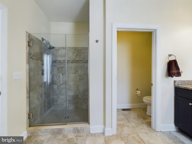 bathroom featuring vanity, toilet, and a shower with door