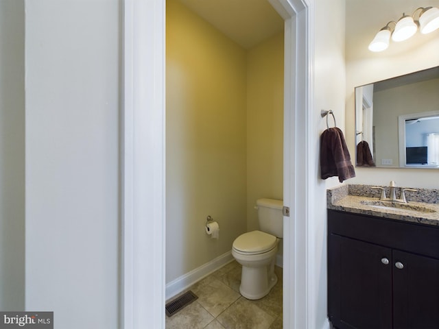 bathroom with toilet, vanity, and tile patterned floors