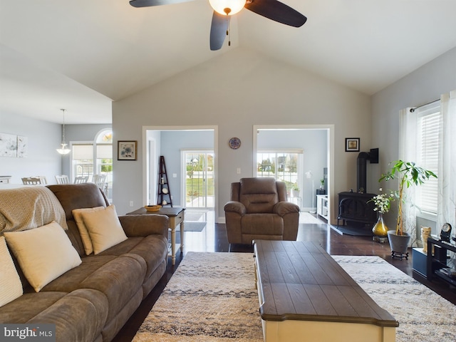 living room with ceiling fan, a wood stove, a wealth of natural light, and dark hardwood / wood-style flooring