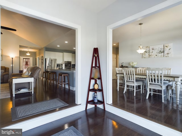 dining area with ceiling fan, vaulted ceiling, and dark hardwood / wood-style floors