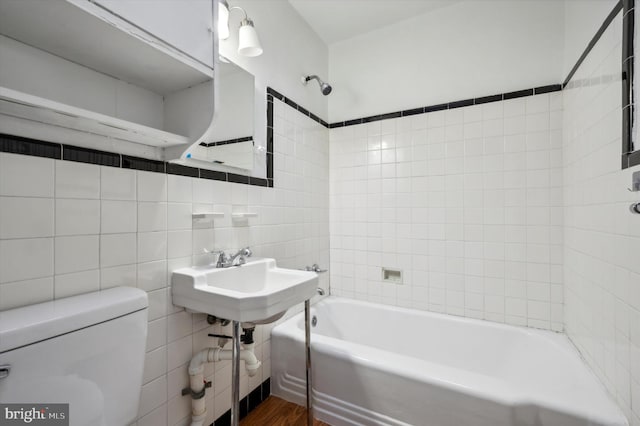 full bathroom featuring tiled shower / bath, hardwood / wood-style floors, tile walls, toilet, and sink